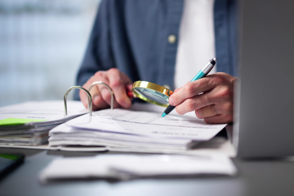 Auditor Using Magnifying Glass For Audit - Trade Info podvod