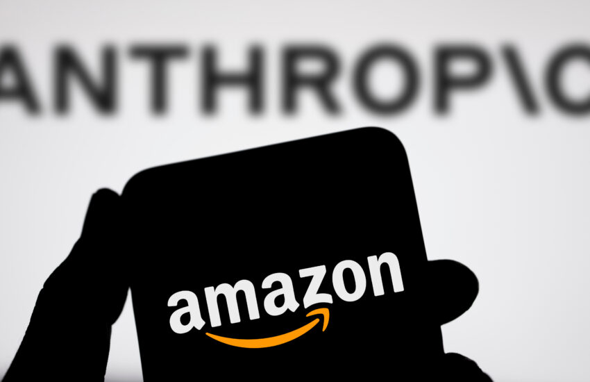 Silhouette of a person holding a large black card displaying the Amazon logo.