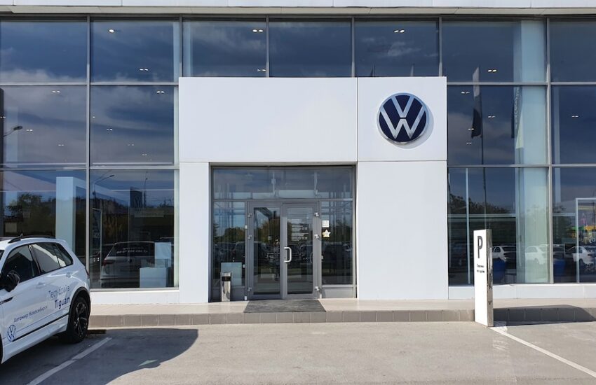 Front view of a Volkswagen dealership with glass facade and a blue VW logo above the entrance.