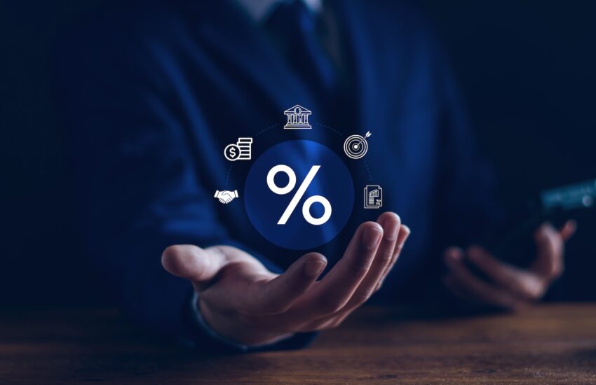 Center: large white percent symbol surrounded by finance icons representing banking, loans, and rate concepts, held by hands in a dark blue background.