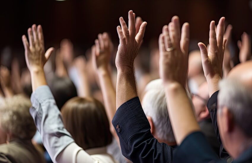 Crowd at a conference with hands raised in the air.